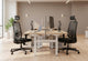 Two Fokus Comfort Chairs are prominently featured in a modern and bright office environment. These black ergonomic mesh office chairs offer excellent support for long hours of work, making them ideal for any productive workspace. The chairs are positioned at light wood desks with white legs, showcasing a comfortable and functional office setup. This image highlights the sleek design and practical features of the chair, perfect for businesses seeking high-quality office seating solutions.