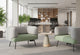 Two Omni Curved Arm Lounge Chairs are positioned facing each other across a small, modern round table in a bright, open-plan office environment. Each lounge chair, featuring a sculptural silhouette with gently contoured pebble grey backrests and dusty teal seats upholstered in polyester OTE fabric. The setup creates an inviting collaborative workspace or breakout space for informal meetings or focused individual work